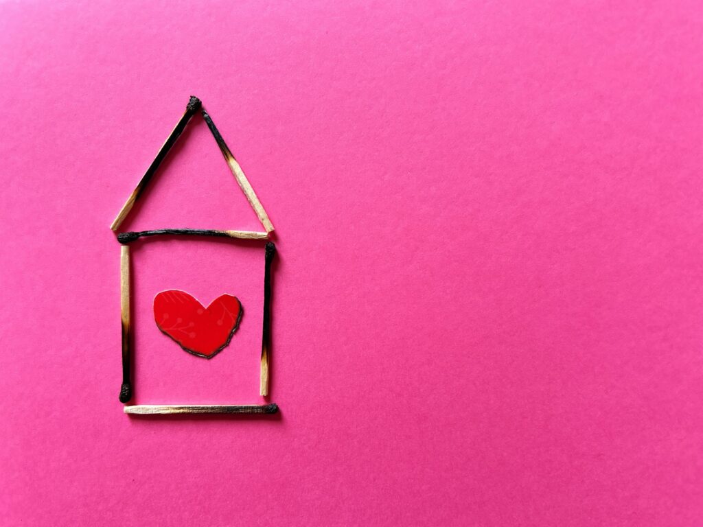 House outline made of burnt matches with red heart.